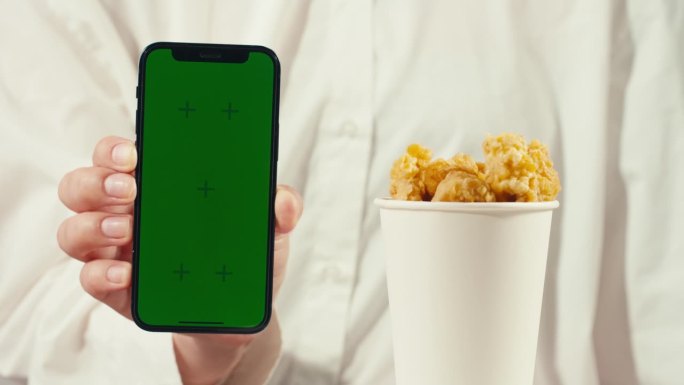 手机外卖应用带色度键绿屏，餐点鸡块和炸鸡薯条，放在木桌上即可外卖。肥美的美国菜。