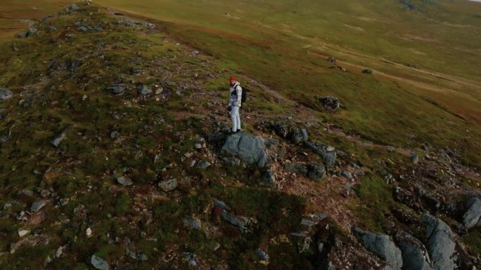 360度的年轻男性背包客站在悬崖边缘，观察罗弗敦群岛的壮丽景色