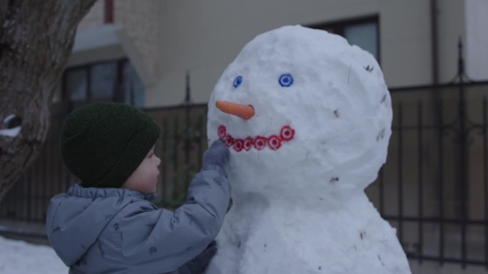 小孩小孩男小孩从雪里堆雪人冬天的一天游戏孩子们在户外