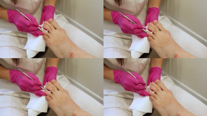 在Spa沙龙接受古典足疗的女性腿部，切割脚指甲角质层。腿部和指甲皮肤护理。足疗程序和SPA过程。特写