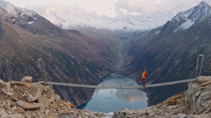 女子站在桥上，以奥地利阿尔卑斯湖为背景