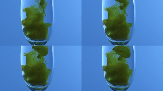 绿色流体在蓝色背景的杯子中形成形状