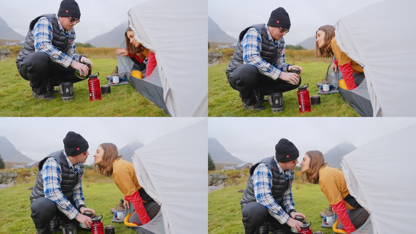 一对浪漫的夫妇穿着暖和的衣服在寒冷的天气里露营。早上醒来亲吻