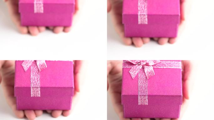 闪闪发光的粉色礼盒，近距离。手把礼品盒放在桌子上，赠送礼物。生日派对的礼物概念。