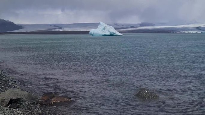 冰川前的冰山在寒冷的海水中，在戏剧性的天空下，露出倾斜
