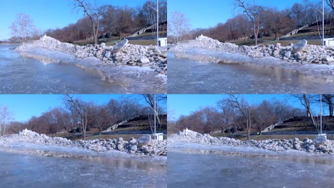 无人机在结冰的河边拍摄了一个公园，河边有成堆的冰碎片和碎片。