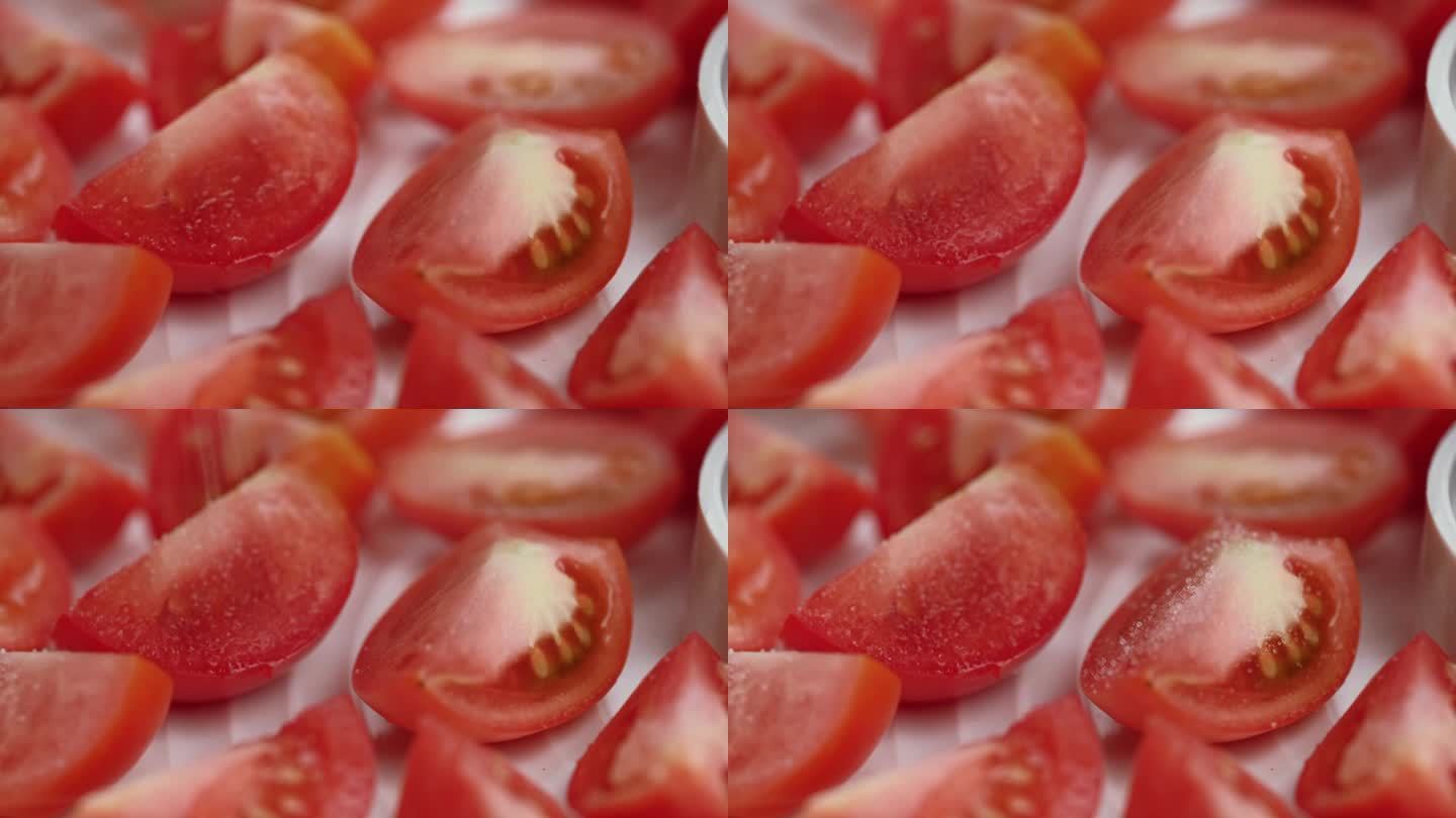 在蔬菜烘干机里把盐撒在新鲜红番茄片上的宏观视频。特写镜头。