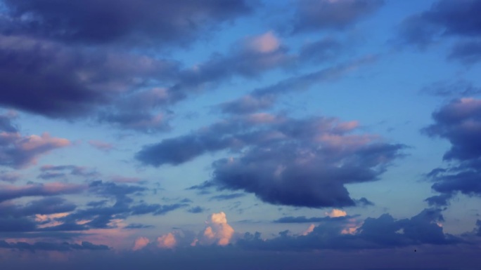 在夜空的延时拍摄中，高云在相反的方向上水平移动，形成了迷人的云景，在多云的日落背景下创造了一个迷人的