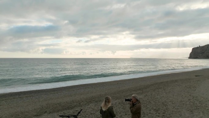 在空旷的海滩上，一对骑着自行车的成熟夫妇的鸟瞰图