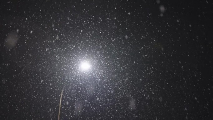 在一个城市的夜晚，一场大雪中的静态慢动作指向一盏路灯