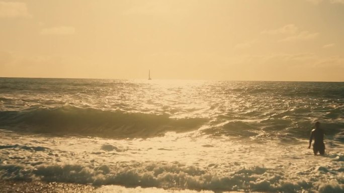 一个男人的剪影在阳光明媚的海浪中玩耍和游泳