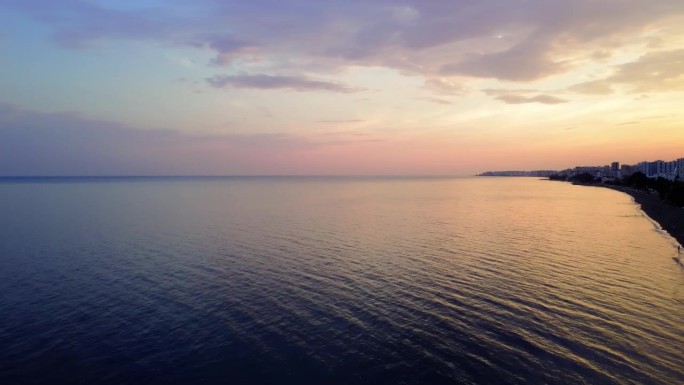 日落时分，土耳其南部梅尔辛地中海海岸线的壮丽鸟瞰图，展示了城市，海滩和宁静的大海，吸引游客体验它的魅