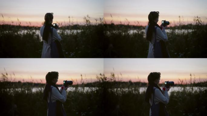 一名身穿优雅长大衣的女子在日落时分拍摄湖边的照片