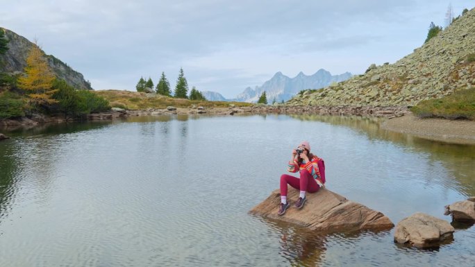 奥地利，一个女人拿着相机坐在湖边