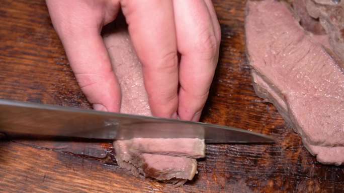 用刀子切在木板上的煮牛肉。高品质4k画面