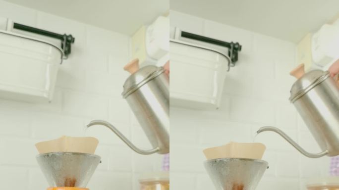 热水倒在手动咖啡滴管在舒适的家庭厨房-垂直镜头。
