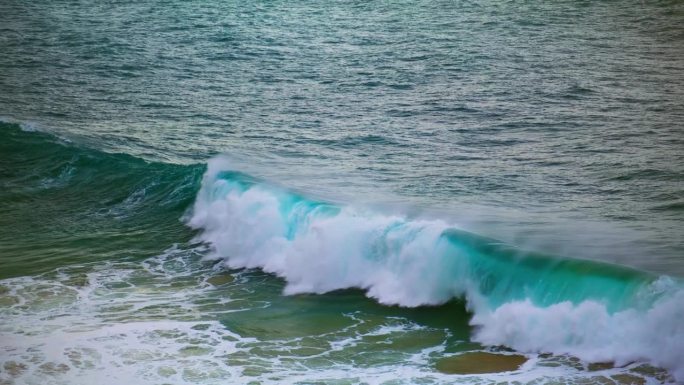 巨大的海浪在浅滩上膨胀破碎。碧绿的海浪翻滚着海岸