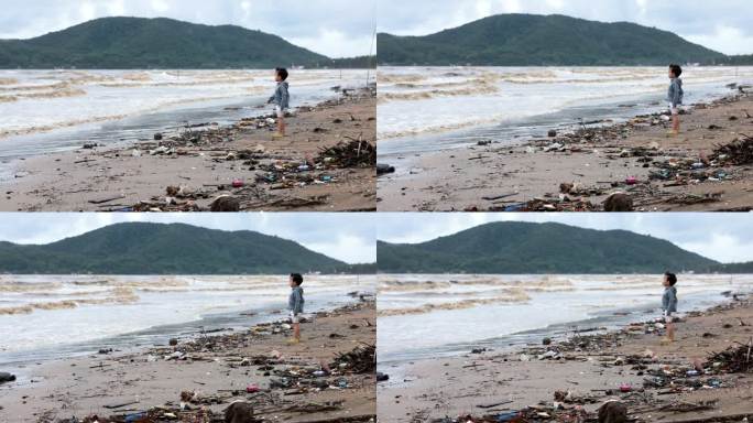 男孩站在海滩上，鱼死了，海滩上的塑料污染没完没了。