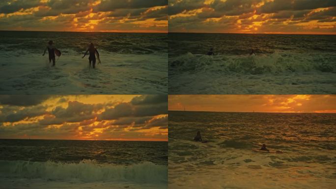 冲浪夫妇带着冲浪板在日落时分冲向大海