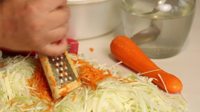 一个男人在家煮酸菜。磨胡萝卜。特写，从侧面看