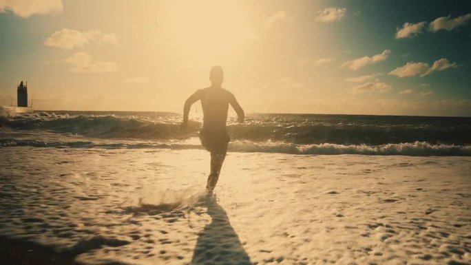 无忧无虑的人跑和跳到阳光明媚的夏天的海洋