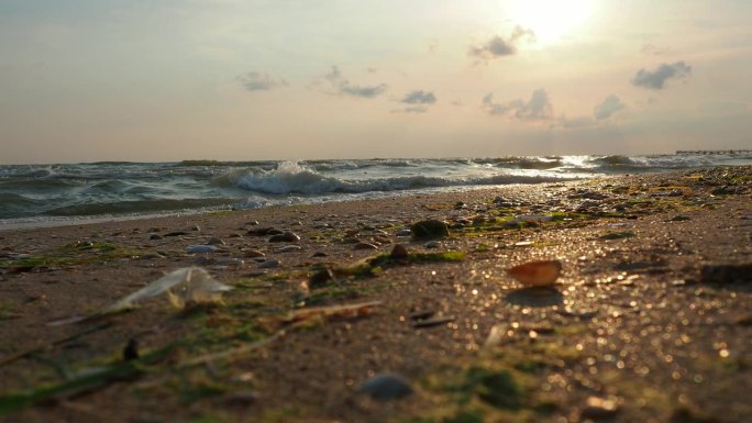 平静的海浪卷过沙滩。日落在海上或海洋。水的运动。海浪掀起阵阵泡沫。旅游的天堂。海滩旅游主题。太阳在波