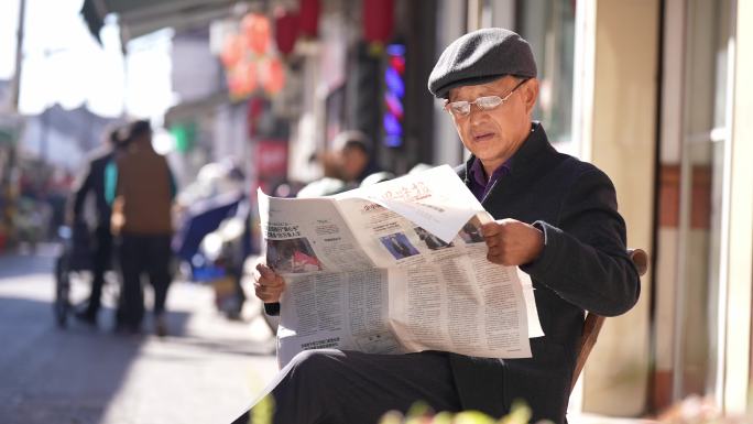 老年人冬天街头阳光下读报看报