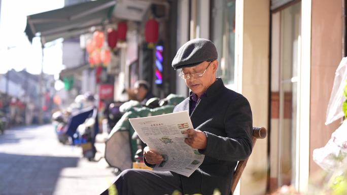 老年人冬天街头阳光下读报看报