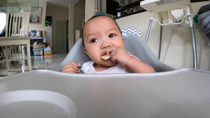 宝宝在家里的餐椅上吃零食的特写