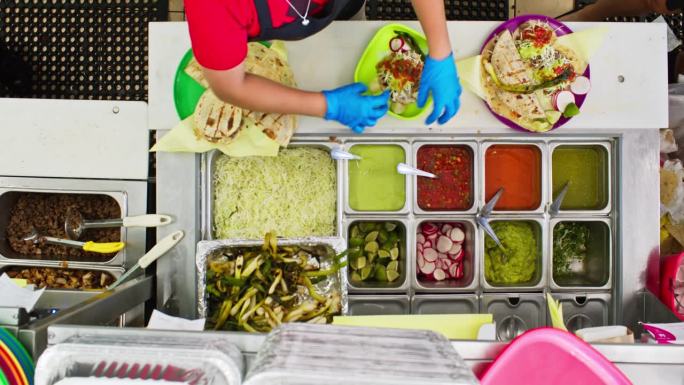 餐厅工人在墨西哥餐厅往菜里加配料的俯视图