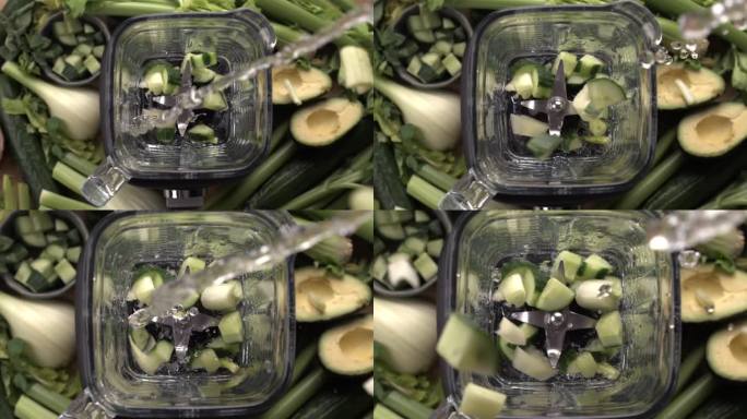 加入水和绿色蔬菜到搅拌器中，用慢动作捕捉，牛油果，芹菜，黄瓜和绿色蔬菜作为背景，准备排毒奶昔