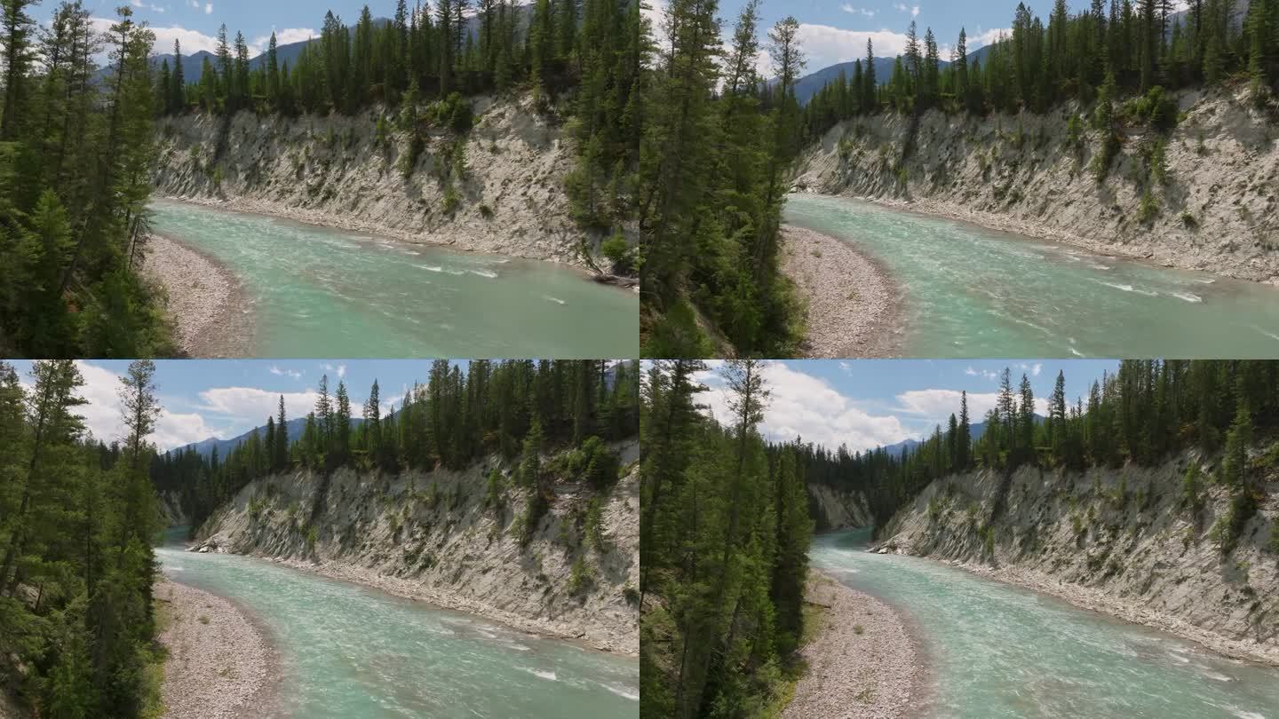 在加拿大不列颠哥伦比亚省，无人机沿着库特尼河飞过峡谷，透过树木可以看到落基山脉