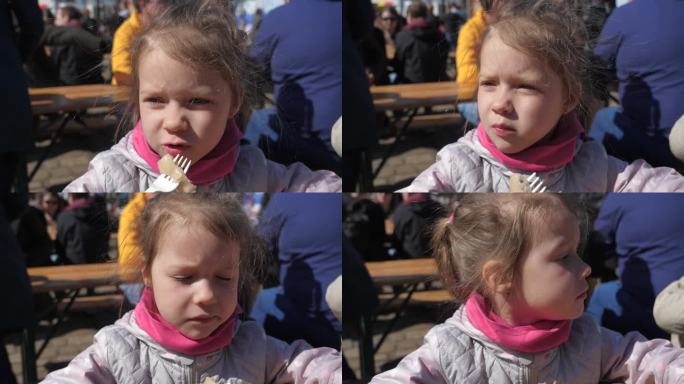 街头美食节上，小女孩用塑料叉子嚼着亚洲饺子