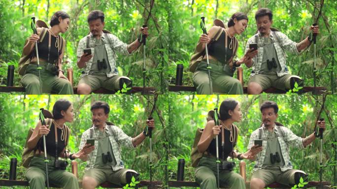 中年成年残障男子戴着双筒望远镜，坐在树干上与亚洲女性交谈，用手机讨论森林徒步旅行的方向规划，幸福的亚