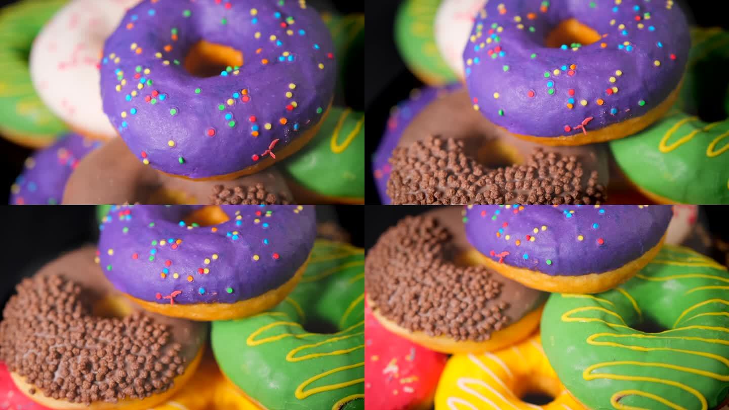 各式各样的甜甜圈旋转着，黑色背景上点缀着巧克力磨砂、紫色釉面和糖屑。