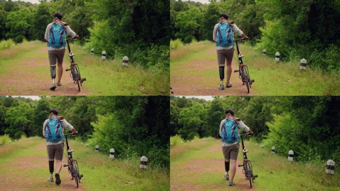 亚洲残障男子，带着假肢，骑着自行车，走在靠近森林的自然学习路线上的土路上，中年成年男性，喜欢散步和自