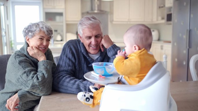 快乐的祖父母一起在厨房喂宝宝，爱和有趣的家庭纽带在家里。微笑，食物和老人，妇女和饥饿的孩子在公寓吃午