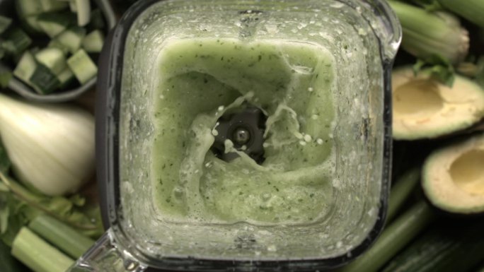 在搅拌机内混合绿色奶昔，以每秒高帧数的慢动作捕捉。从俯视图看排毒饮料的制备