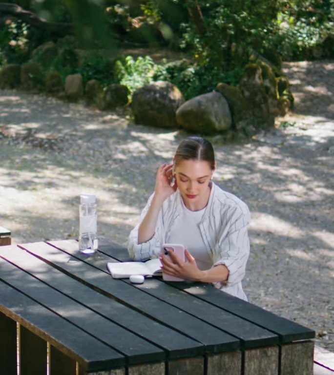 放松的女人说视频会议手机垂直坐在野餐点