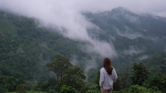 一个女人在雾天看美丽的山景