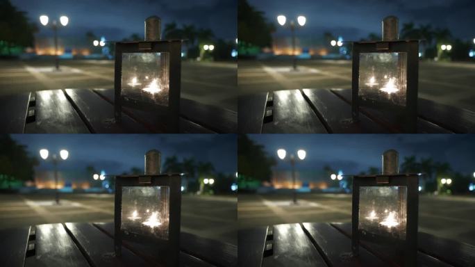 夜景外餐厅的空木桌上的装饰蜡烛灯近照。街灯在广场上模糊的背景