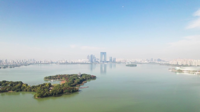 无人机在中国江苏省苏州市金鸡湖上空飞行。在阳光明媚的秋日鸟瞰苏州美丽的湖景和地标，4k实时镜头。