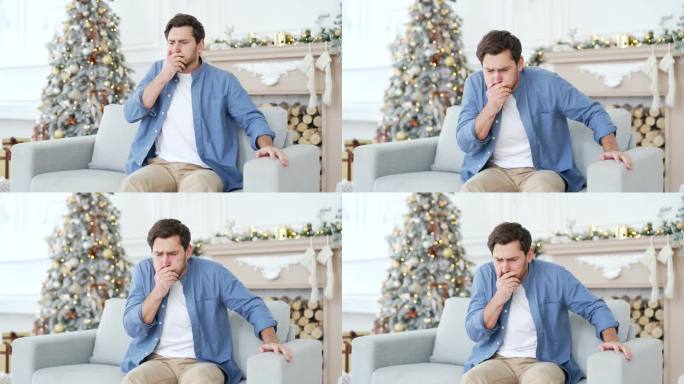 一名男子在冬季、新年、圣诞节、圣诞节期间，坐在家里客厅的沙发上，恶心得想吐