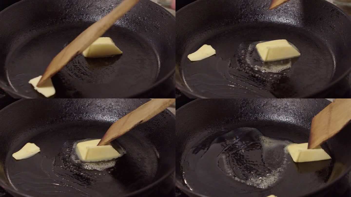 特写:一小块黄油在热铁锅里融化，用木抹刀搅拌