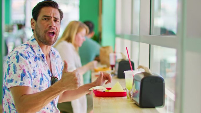 一名男子在吃墨西哥食物时对着镜头竖起大拇指