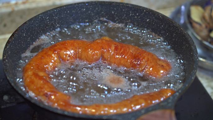 一位厨师在用平底锅油炸猪大肠，炸猪七寸