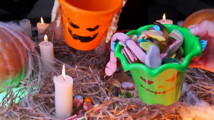 在万圣节的背景下，一桶桶的糖果燃烧着蜡烛和传统的南瓜，孩子们收集糖果并分享糖果