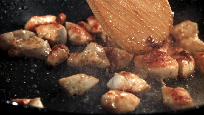 在煎锅里翻炒鸡肉。用高速摄像机拍摄，每秒1000帧。