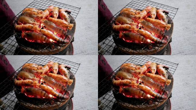在泰国曼谷的一个大排档上，用火红的煤在烤架上烤大虾。
