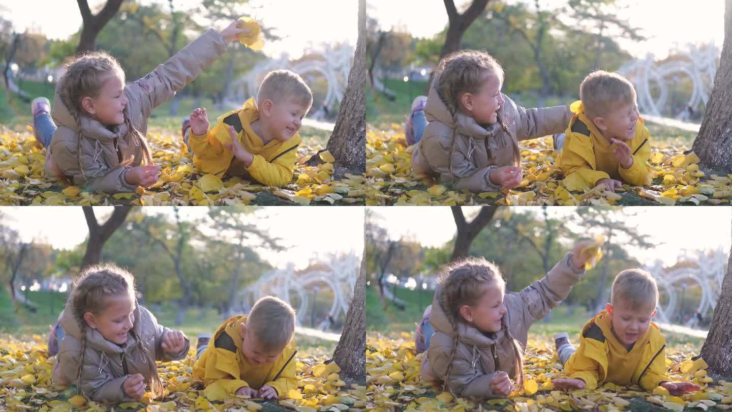 哥哥和妹妹在秋天的公园里玩耍。孩子们一边扔树叶一边笑。